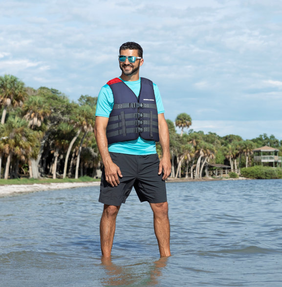 man in water with life jacket, smiling in the sun. 